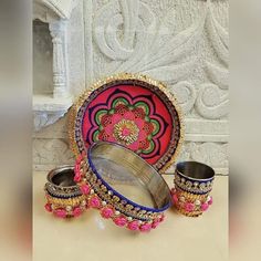 an ornately decorated plate and two matching cups are on display in front of a white wall