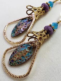 Hand-Painted Earrings. The centerpiece of these earrings are the beautiful hand-painted on copper with resin charms made by Washington State artist Kristi. I accented them with rounded triangle connectors, vintage brass bead caps, purple faceted Czech glass beads and turquoise Swarovski crystal bicone beads. These earrings are 3 inches long including the pure brass round lever back closures. One Of A Kind I can send it gift wrapped (free of charge), if requested. Gold Teardrop Earrings With Artistic Design, Artsy Copper Drop Earrings, Gold Teardrop Jewelry With Artistic Design, Handmade Bronze Czech Glass Earrings, Hand Painted Gold Metal Jewelry, Handmade Gold Enamel Earrings, Artsy Copper Jewelry With Matching Earrings, Artsy Gold Earrings Made Of Copper, Handmade Enamel Teardrop Jewelry