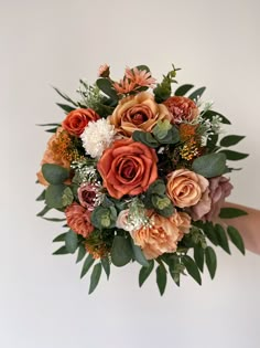 a bridal bouquet with orange and pink flowers on it is being held by someone