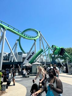 people are standing in front of the roller coaster