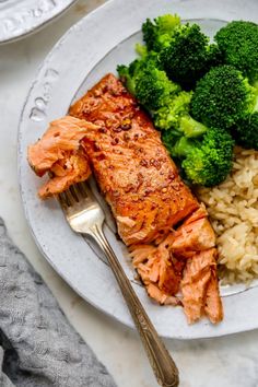 salmon, broccoli and rice are on a plate with a fork next to it