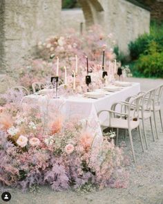 an outdoor table set up with flowers and candles for a formal dinner or wedding reception