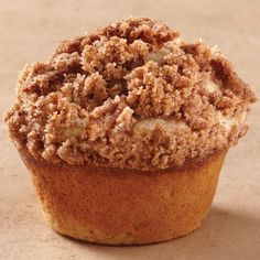 a muffin with crumbs on top sitting on a table next to a cupcake