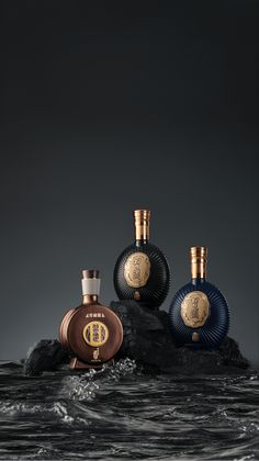 three bottles of perfume sitting on top of a rock in the water