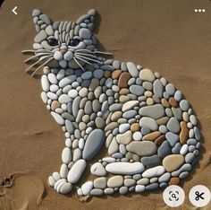 a cat made out of rocks sitting on the sand