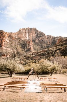 an outdoor ceremony setup with wooden benches and mountains in the background