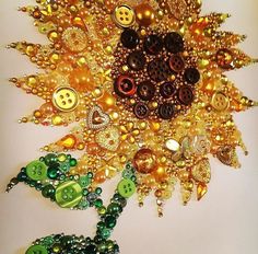 a sunflower made out of buttons and beads on a white surface with other items