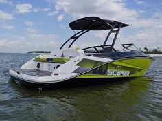 a green and white boat in the water with its canopy down on it's side