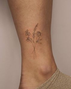 a small flower tattoo on the side of a woman's leg, with flowers growing out of it