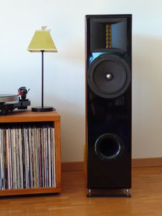 there is a speaker next to a record player on the floor in front of a lamp