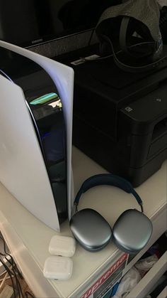 a computer monitor sitting on top of a desk next to a printer and headphones