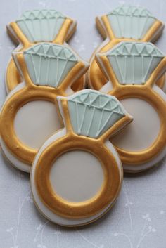 four decorated cookies in the shape of rings with diamonds on each one and gold trimmings