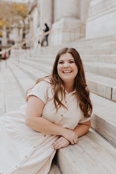 a woman sitting on steps in front of the supreme court building smiling at the camera