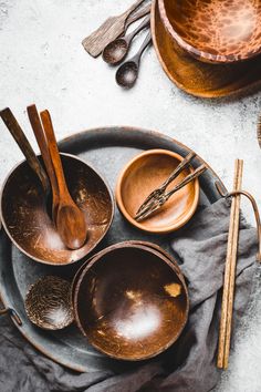 wooden spoons and bowls on a plate with utensils in the bowl next to them