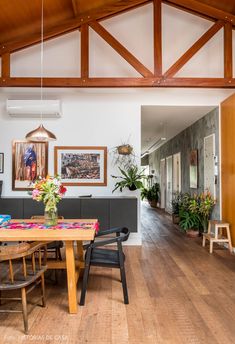 a dining room table with chairs and pictures on the wall above it, along with potted plants