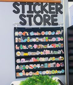 there is a sign that says sticker store next to a potted plant in front of it