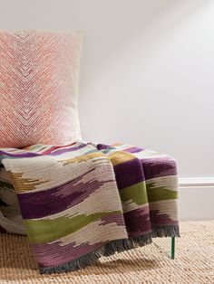 a colorful blanket sitting on top of a chair next to a pillow