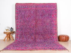 a pink and purple rug sitting on top of a wooden floor next to a table