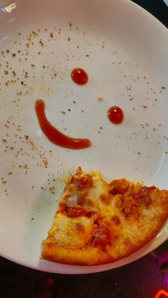 a slice of pizza sitting on top of a white plate with a smiley face drawn on it