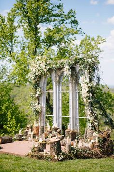 an outdoor ceremony setup with white flowers and greenery on the ground, surrounded by trees