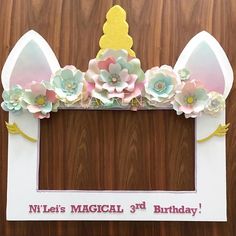 a photo frame decorated with paper flowers and bunny ears for a child's birthday