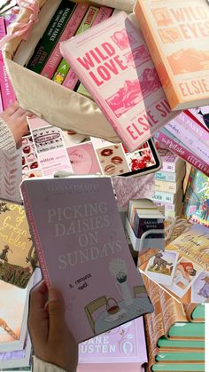 a person holding up a pink book in front of many other books