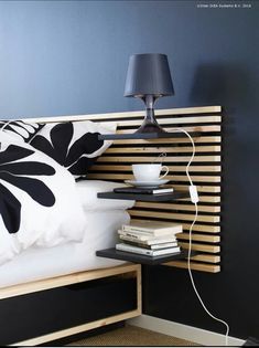 a bed that has some books on it and a lamp in the corner next to it