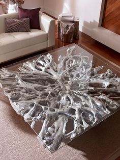 a glass coffee table sitting on top of a wooden floor next to a white couch