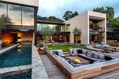 an outdoor living area with couches and fire pit in front of a modern home