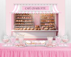 a pink table topped with lots of donuts and cupcakes next to a display case