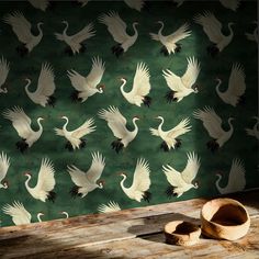 a wallpaper with white birds on it in front of a wooden table and bowl