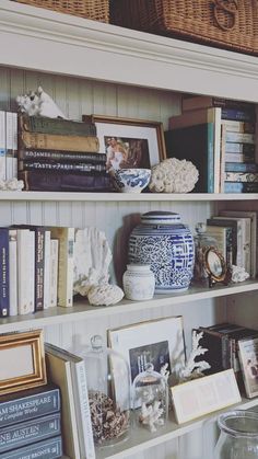 a shelf with books, vases and pictures on it