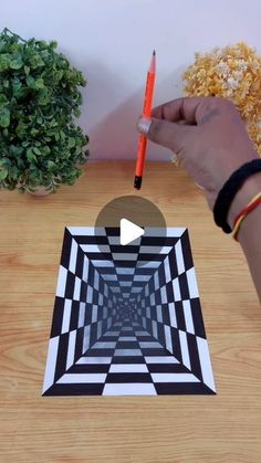 a person holding a pencil in their hand and drawing an optical illusion on a piece of paper