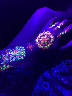 a woman's arm with glow in the dark tattoos on it and her hand