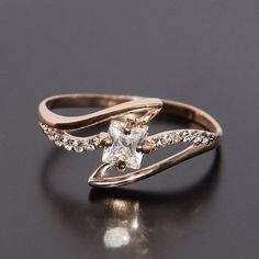 a gold ring with a white diamond in the center on a black surface and some diamonds around it