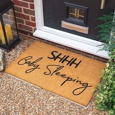 a door mat that says, shih baby sleeping on the front porch next to a potted plant