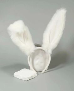 a white rabbit ear hat with feathers on it's head and a small piece of cotton