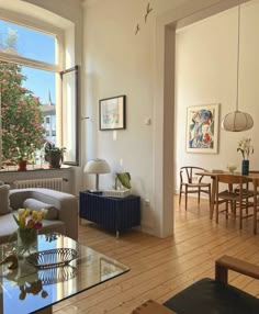 a living room filled with furniture next to a large window covered in plants and flowers