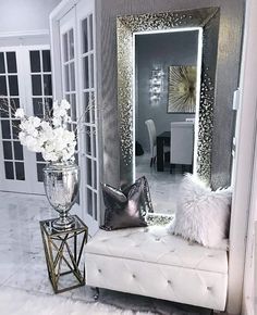 a white bench sitting in front of a mirror and vase with flowers on top of it