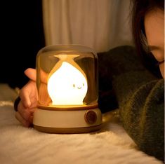 a girl is looking at an alarm clock with a cat in it's glass dome