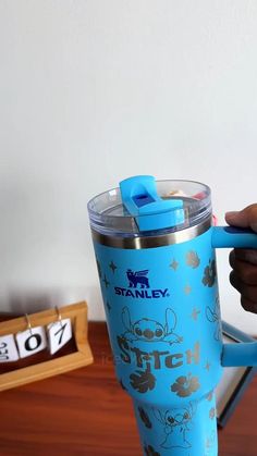 a person is holding a blue cup with the lid up and it's handle in their hand