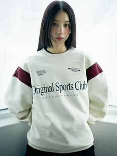 a woman standing in front of a window with her hands on her hips and wearing a white sweatshirt that says original sports club