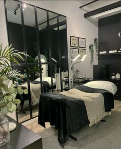 a black and white bedroom with mirrors on the wall, plants in vases next to bed