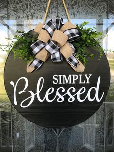 a black and white sign that says simply blessed hanging from a door with a bow on it