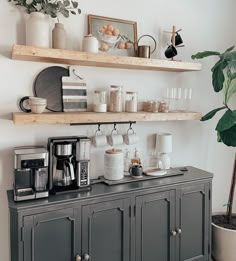 there is a coffee maker and some cups on top of the shelves in this kitchen