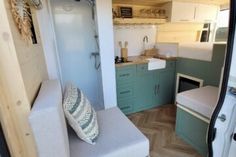 the interior of a tiny home with wood flooring and green cabinets, including a couch