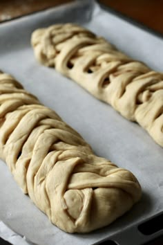 two loaves of bread sitting on top of a baking pan covered in wax paper