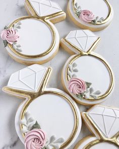 cookies decorated with white and pink icing on a marble counter top next to each other