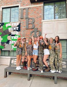 a group of women standing next to each other in front of a brick building holding up signs