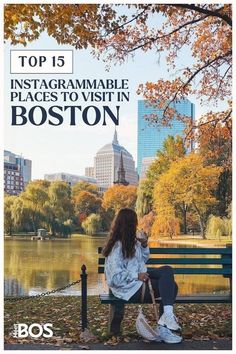 a woman sitting on top of a bench in front of a lake with autumn leaves